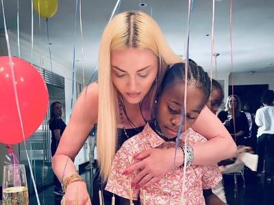 Madonna is cutting the cake as Stelle Ciccone looks on.